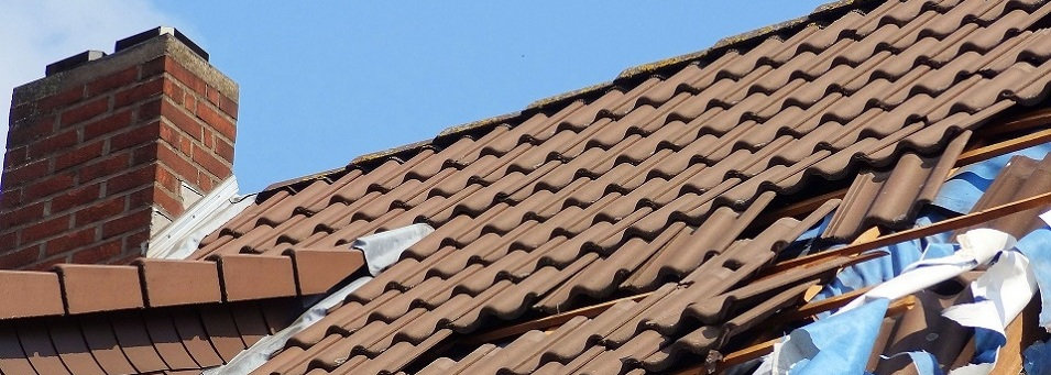 Beschädigtes Hausdach mit fehlenden Ziegeln